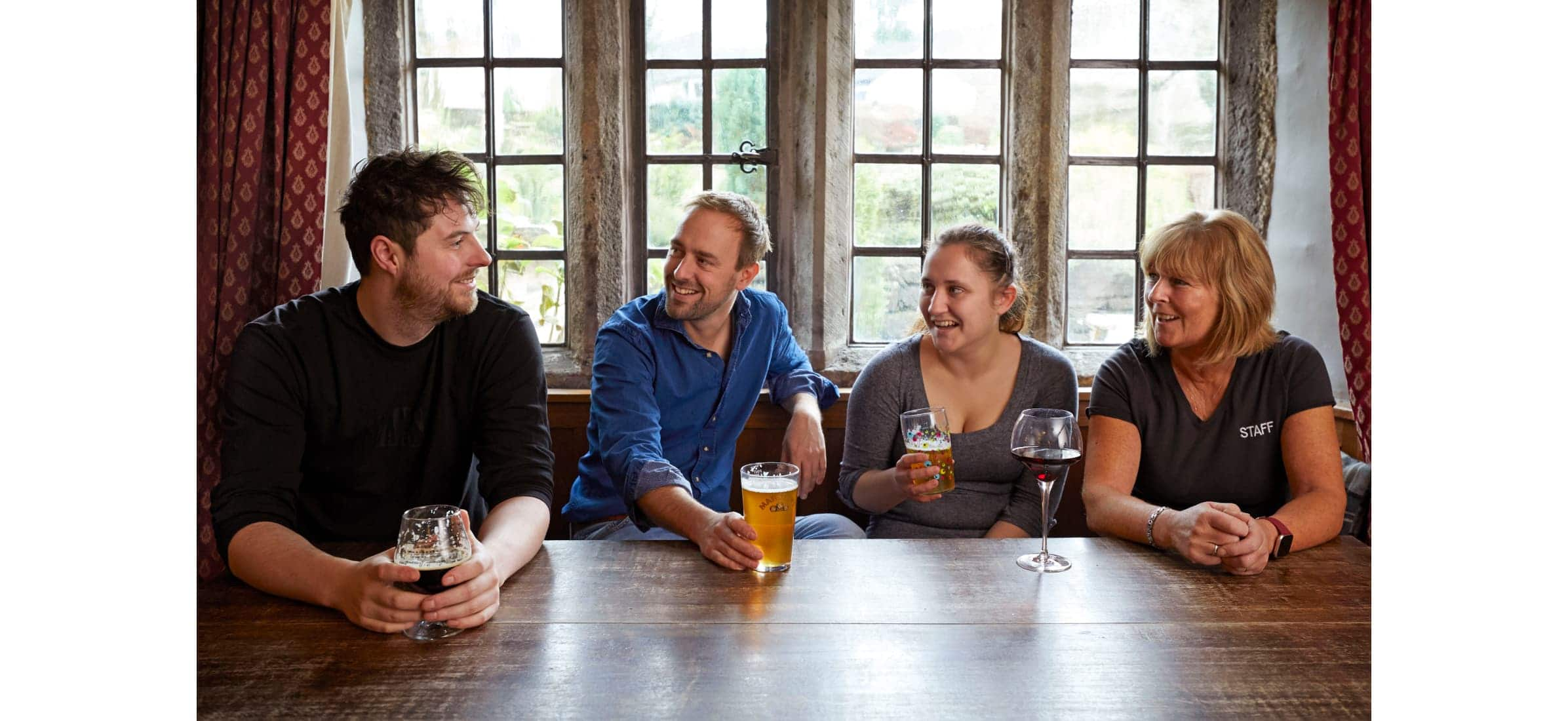 Dan sitting with four other people at a pub table drinking wine and beer.